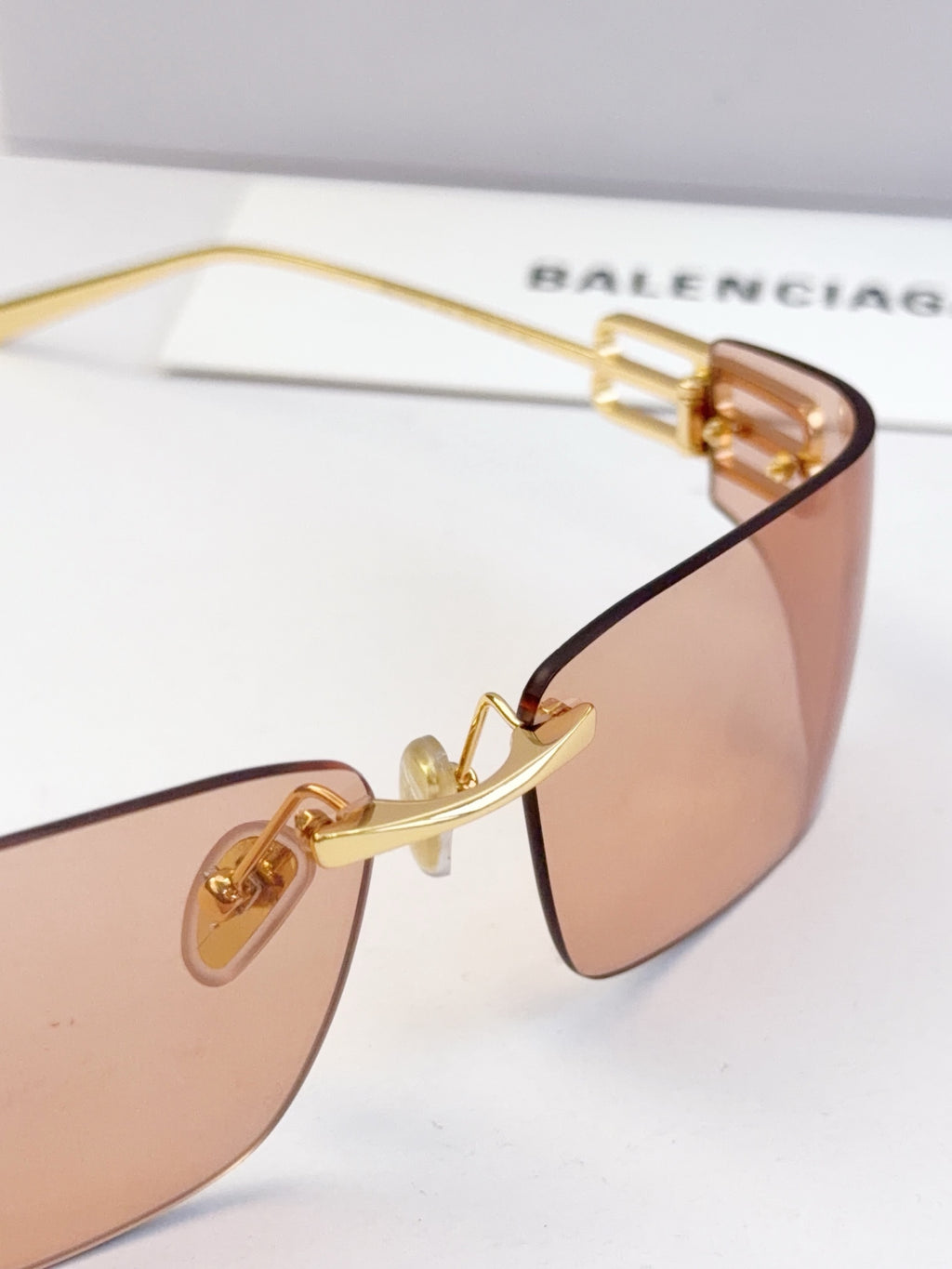 Close-up of gold-tone temple hardware and tinted lens on rectangular frame