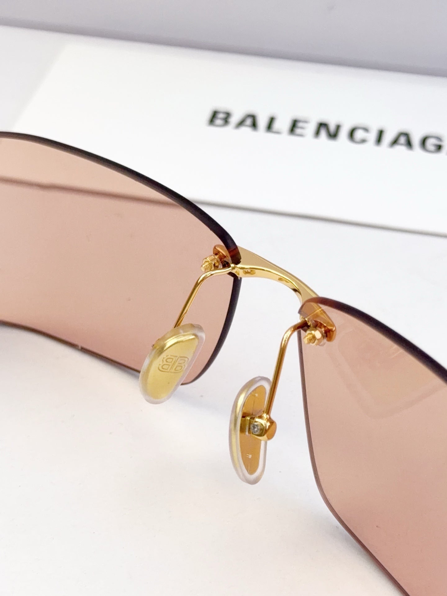 Close-up of gold-tone sunglasses bridge with tinted lens and temple arm
