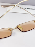 Balenciaga sunglasses close-up, gold-tone frame with tinted lens