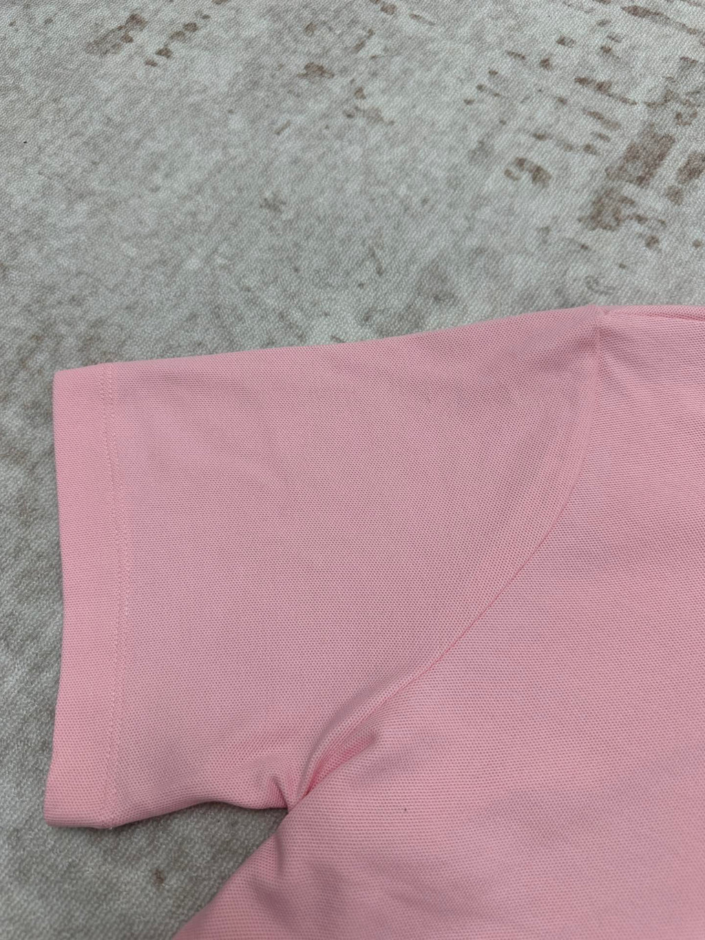 Pink polo shirt fabric close-up at sleeve and side seam