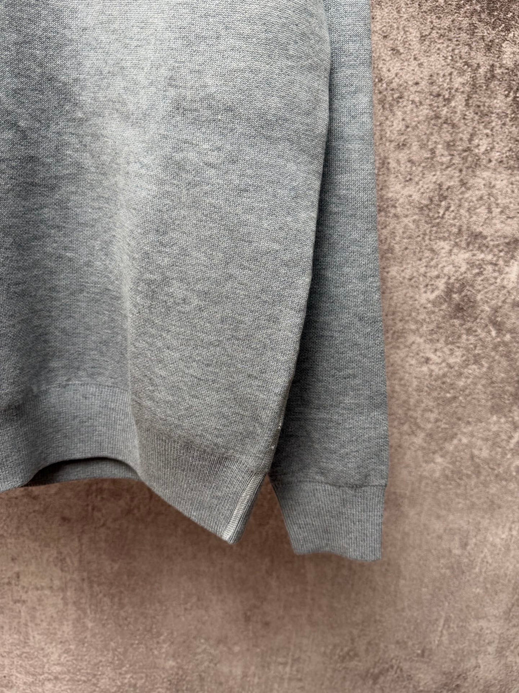 Gray knit sweater sleeve with ribbed cuff and textured knit fabric