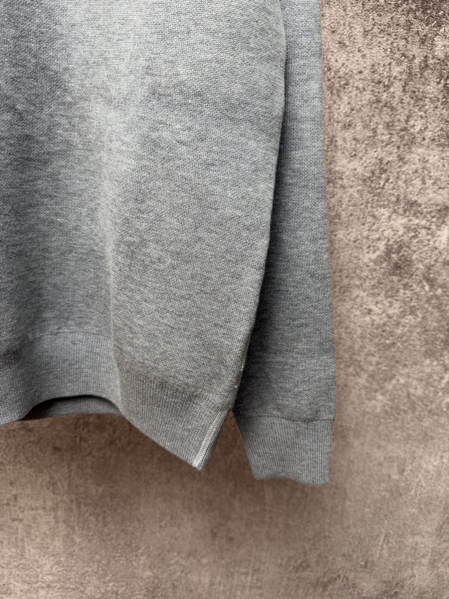 Gray knit sweater sleeve with ribbed cuff and textured knit fabric