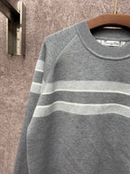 Gray knit sweater with light blue and white horizontal stripes across the chest