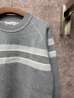 Gray knit sweater close-up with ribbed crew neck and light blue striped band