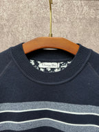 Navy crewneck sweater with light gray and white horizontal stripes near the collar