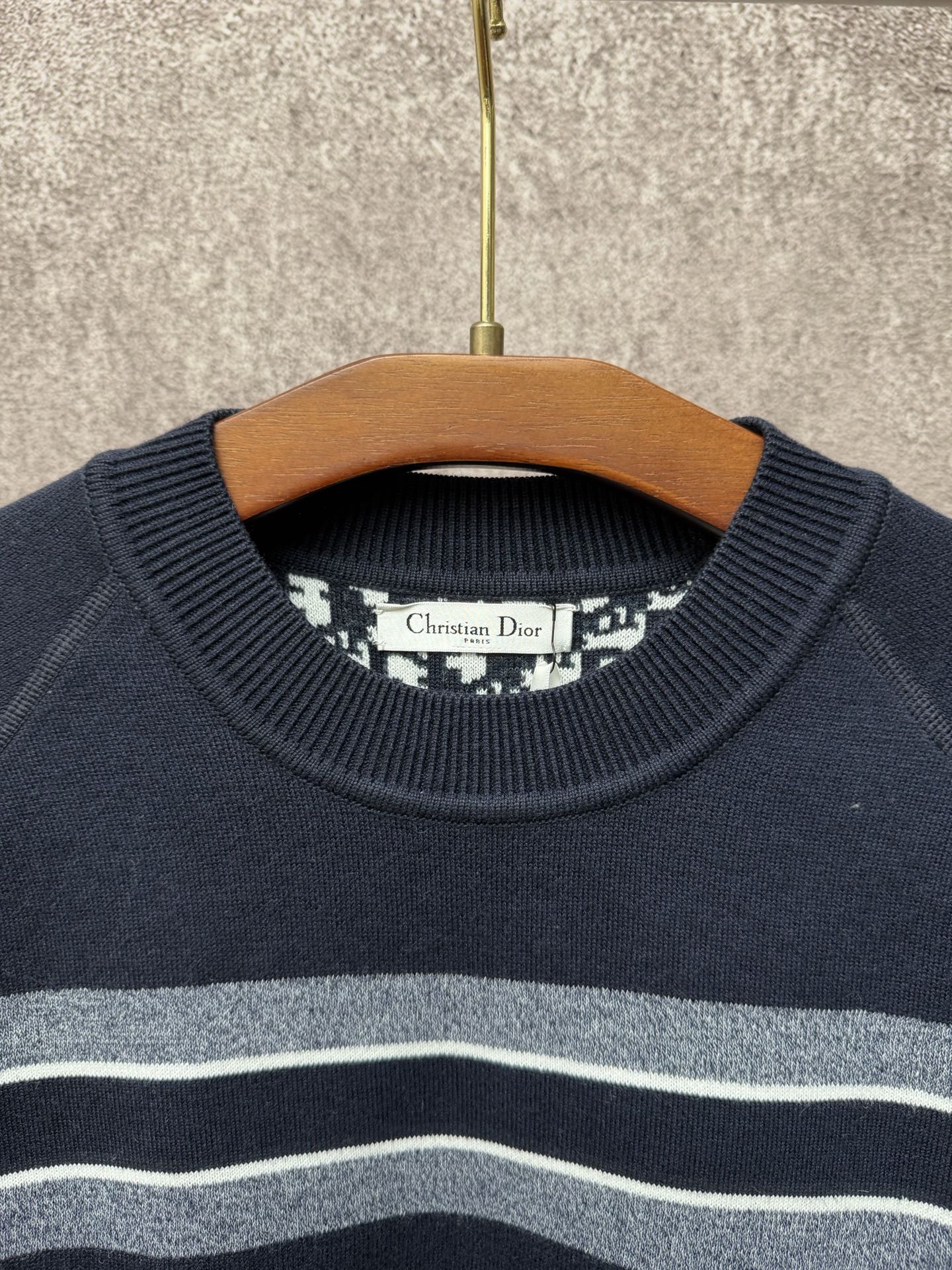 Navy crewneck sweater with light gray and white horizontal stripes near the collar