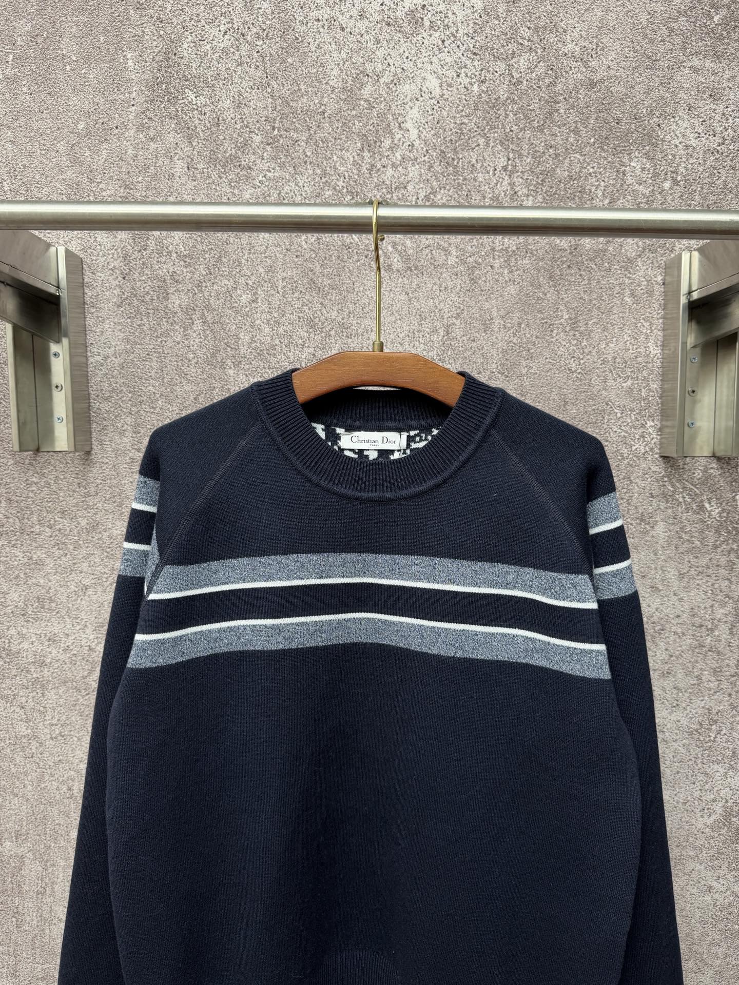Navy long-sleeve knit sweater with light gray and white horizontal stripe bands