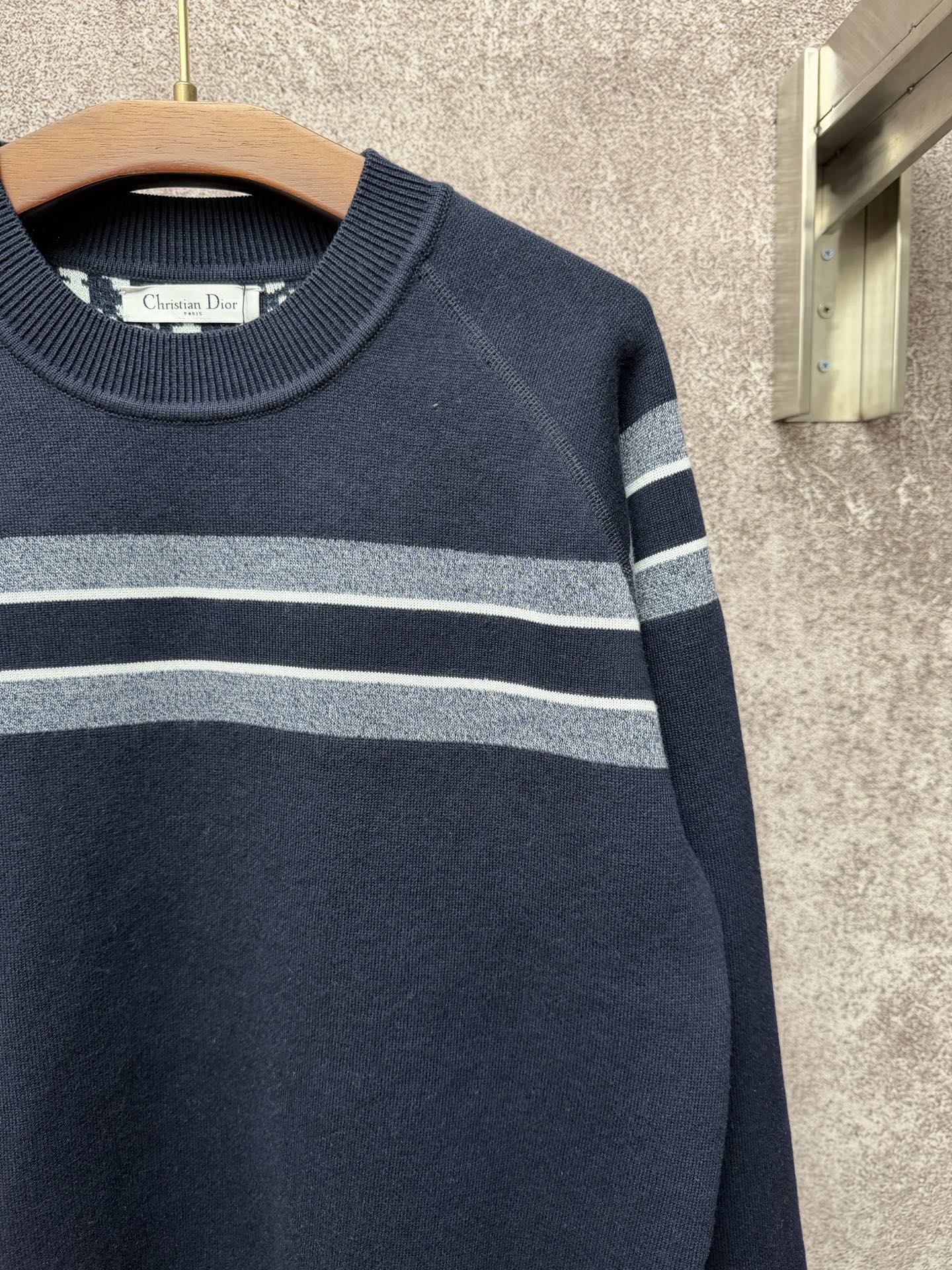 Navy knit sweater with wide light gray and white stripe across the chest and sleeves