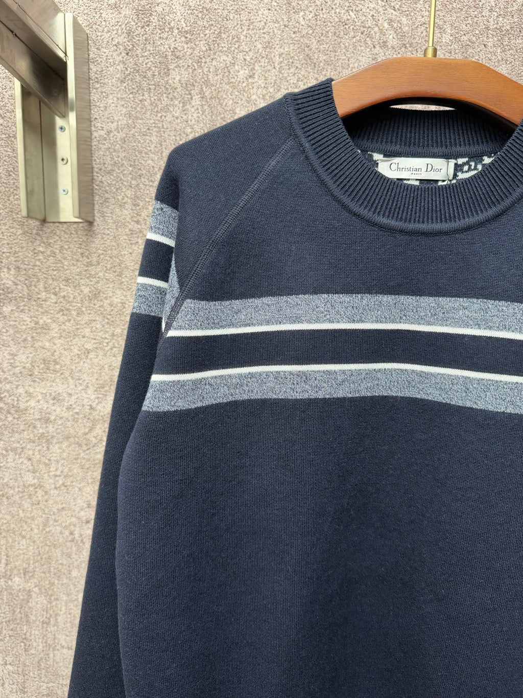 Navy long-sleeve sweater with light gray and white striped bands on upper arms