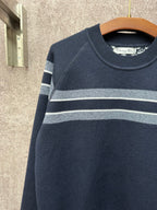 Navy long-sleeve sweater with light gray and white striped bands on upper arms