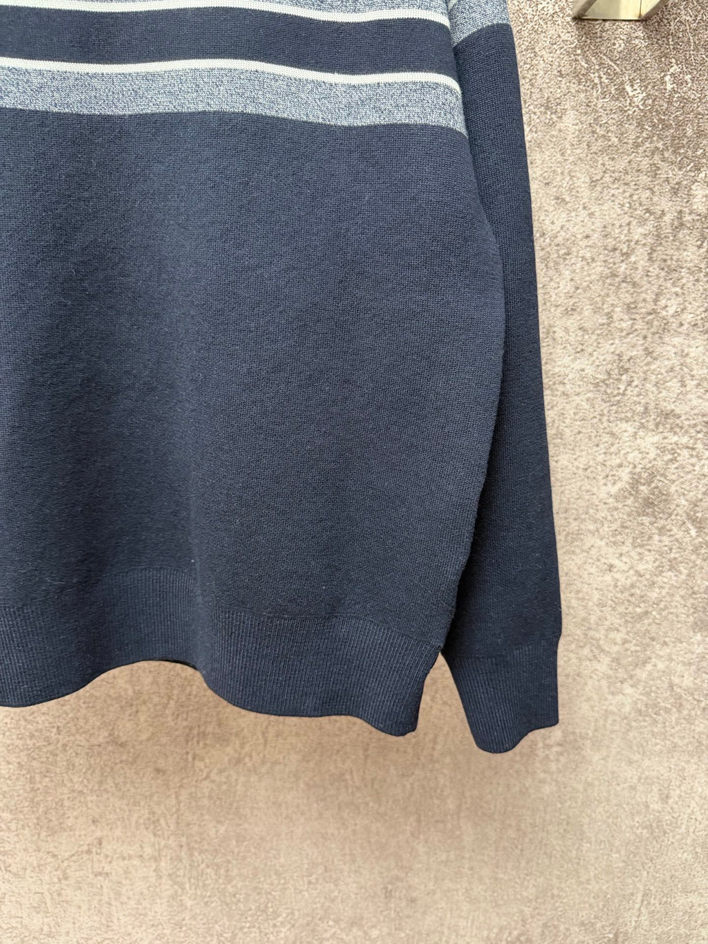 Navy knit sweater hem with light gray and white striped band detail