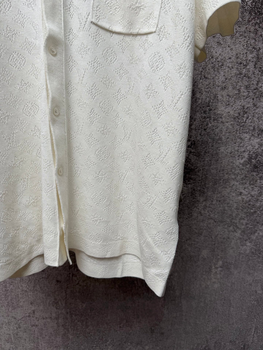 Cream polo shirt hem with button placket and textured fabric