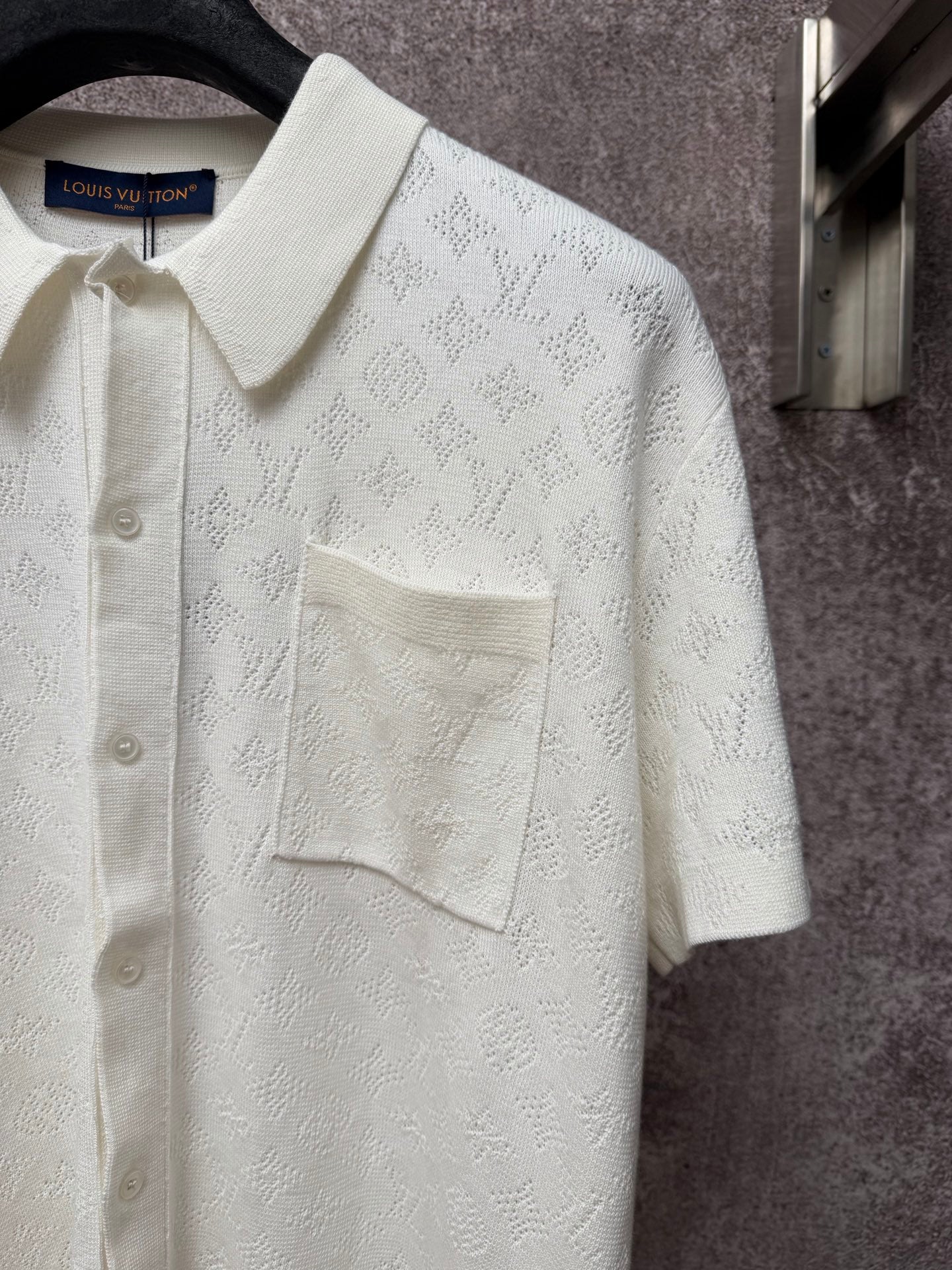Cream polo shirt with textured monogram pattern, point collar, and flap chest pocket