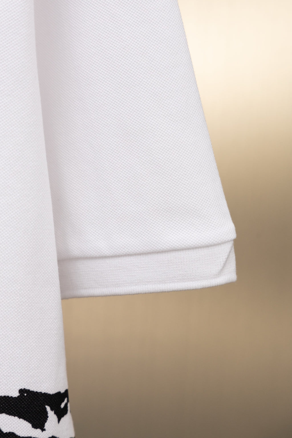 White Burberry polo shirt sleeve hem with black graphic at cuff