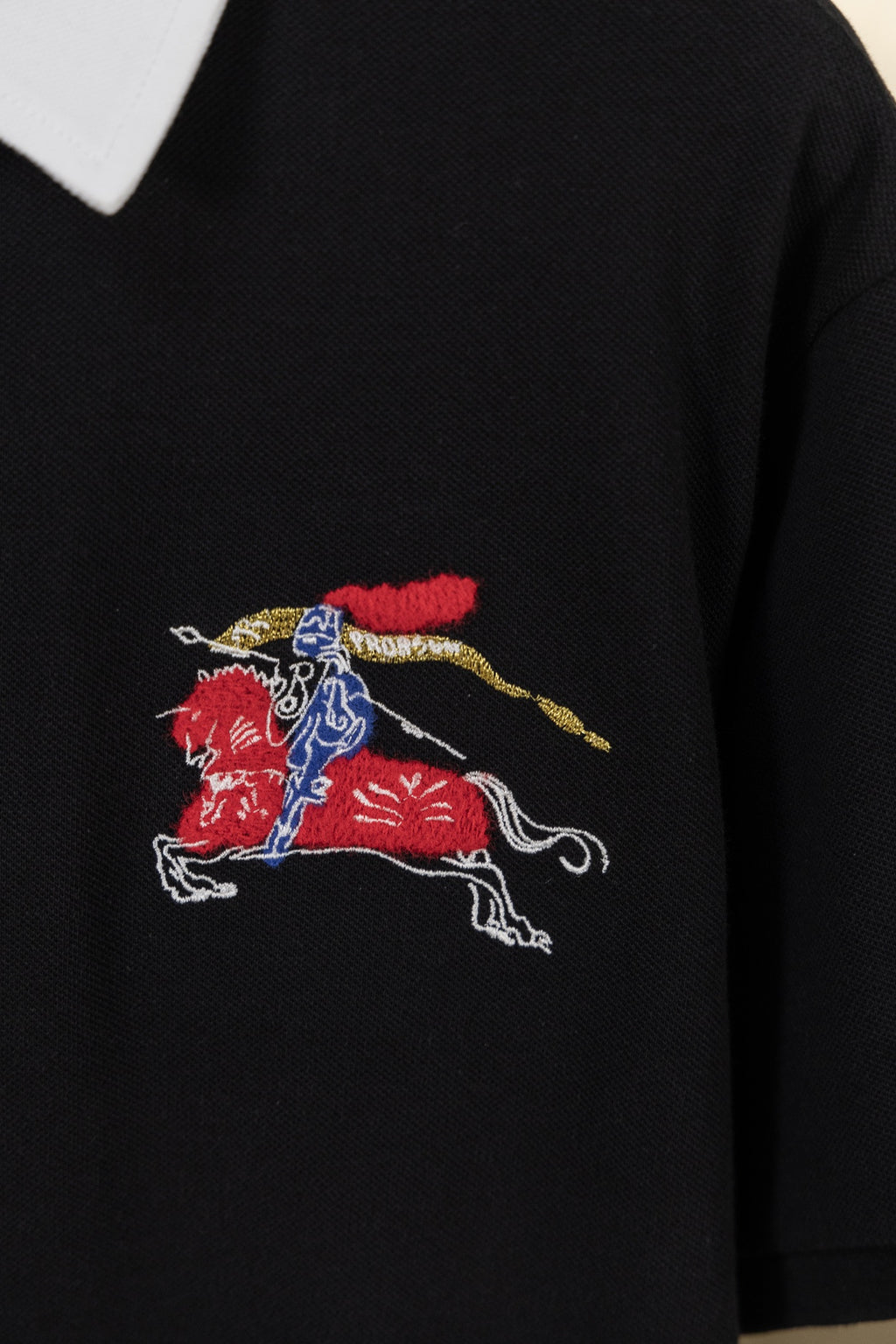 Embroidered knight-and-horse logo on black polo shirt