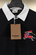 Black polo shirt with white collar, embroidered knight-and-horse logo, and hanging tag