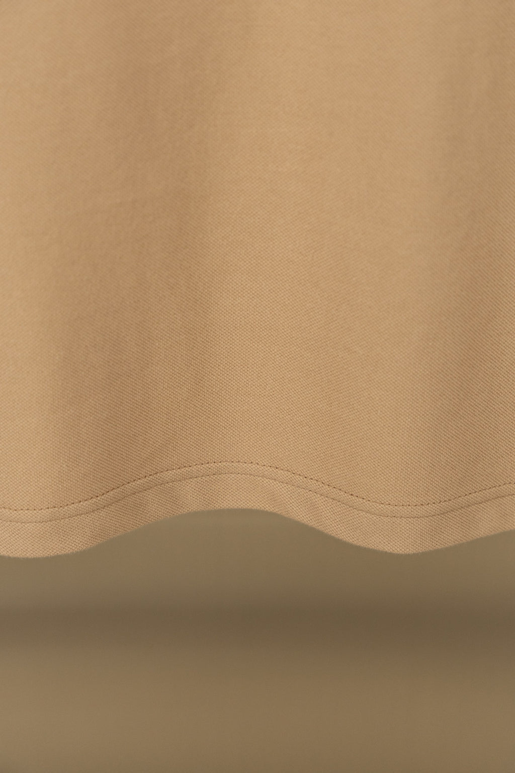 Polo shirt fabric close-up with curved hem seam and visible stitching