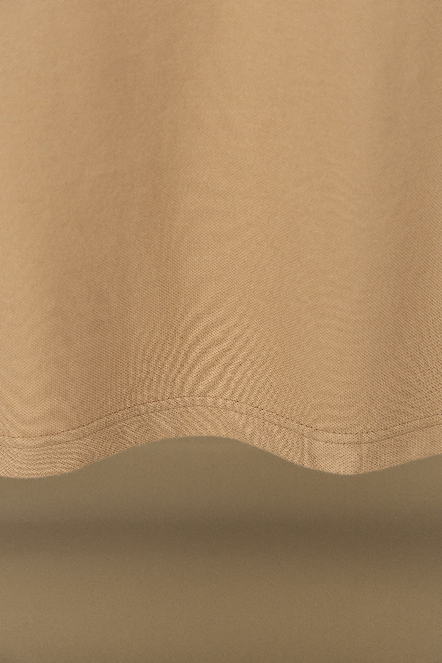 Polo shirt fabric close-up with curved hem seam and visible stitching