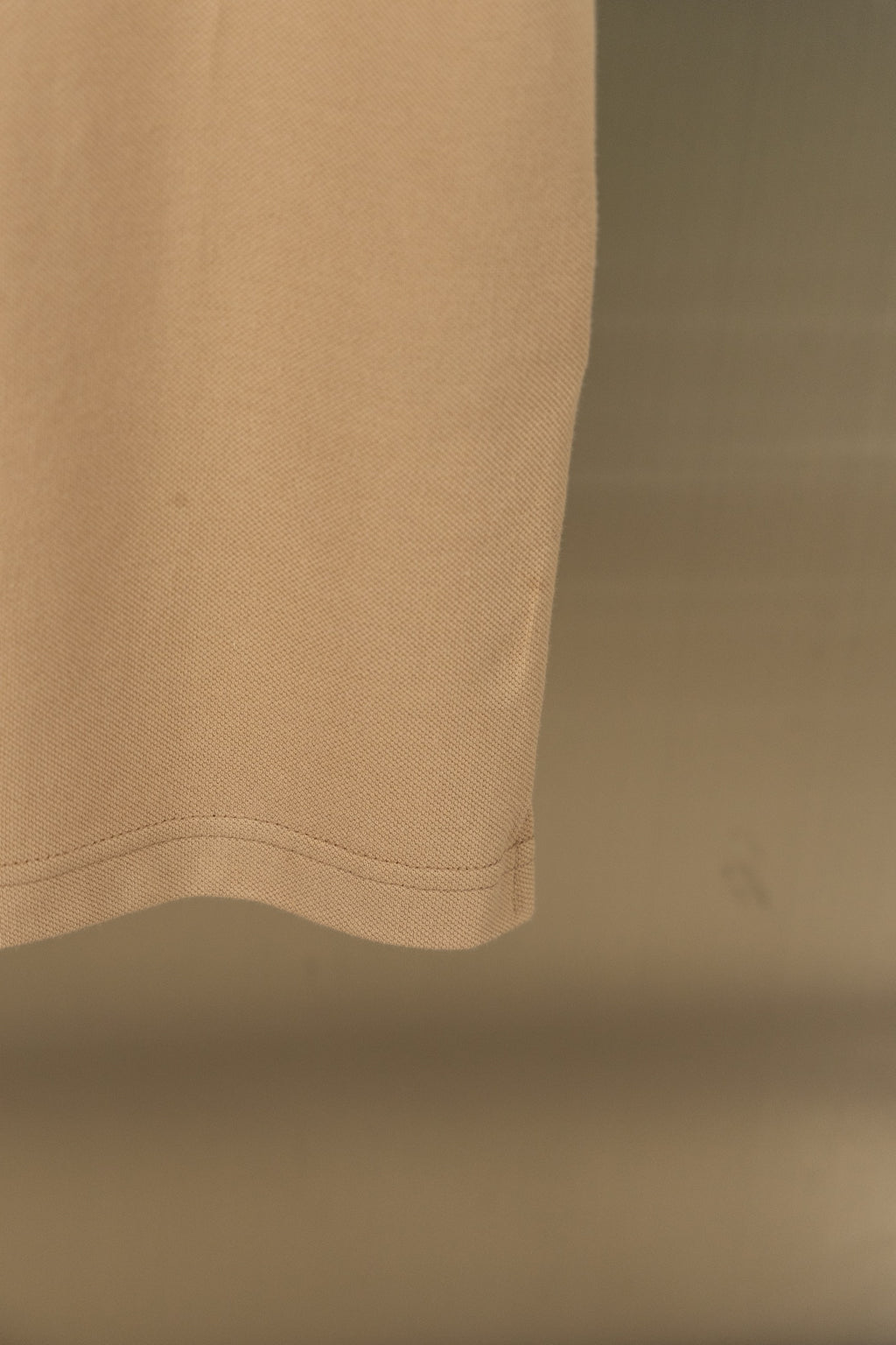 Tan polo shirt hem with subtle stitching at lower edge