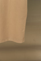 Tan polo shirt hem with subtle stitching at lower edge