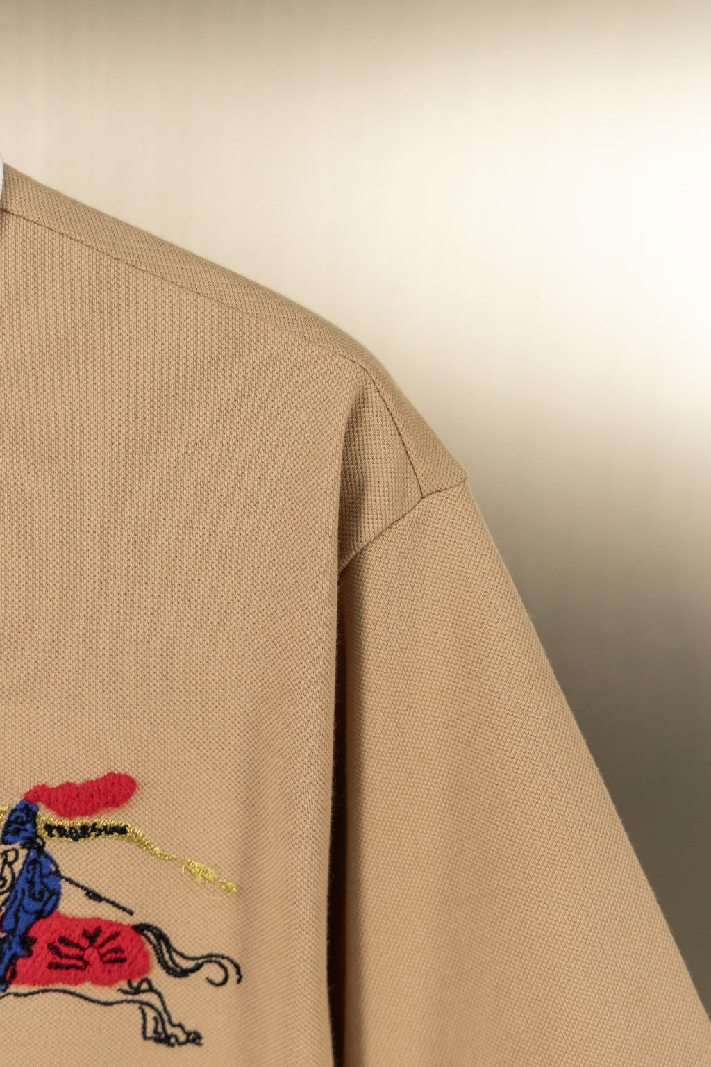 Tan polo shirt sleeve with colorful horse emblem detail