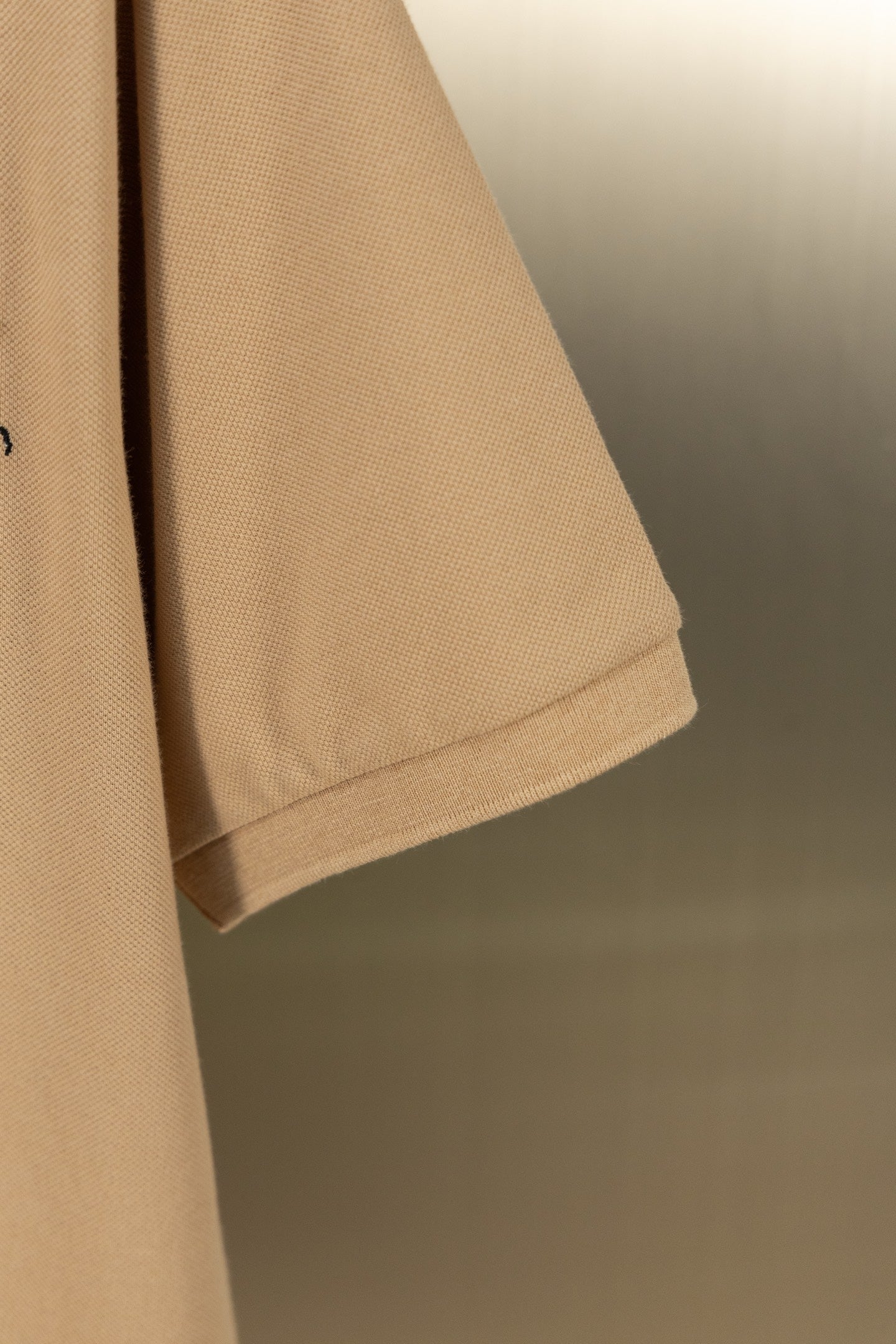Tan polo shirt sleeve hem with stitched cuff edge