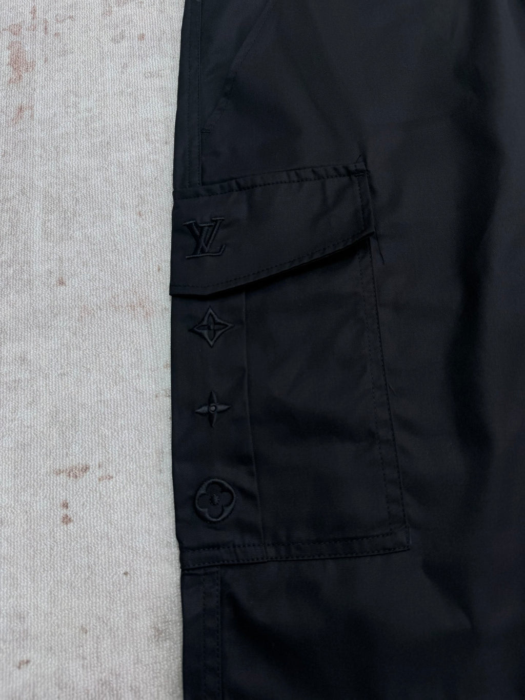 Black cargo pants with stitched emblem patches on pocket flap