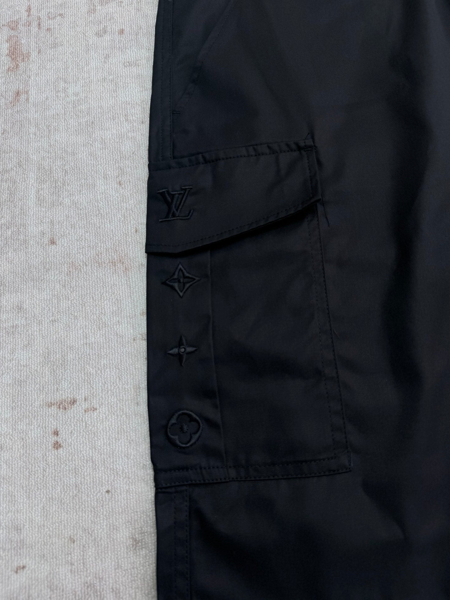 Black cargo pants with stitched emblem patches on pocket flap