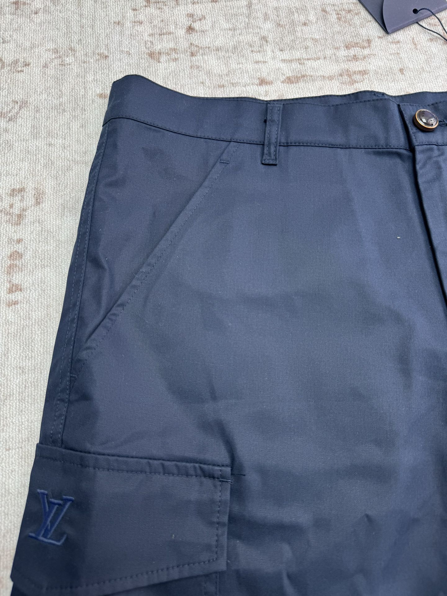 Navy Louis Vuitton shorts front with belt loops and deep cargo pocket.