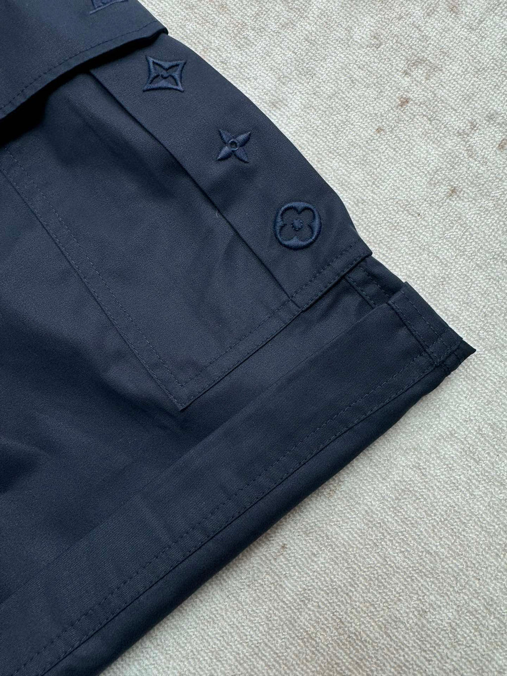 Navy Louis Vuitton shorts with pocket flaps and embroidered star and icon details.