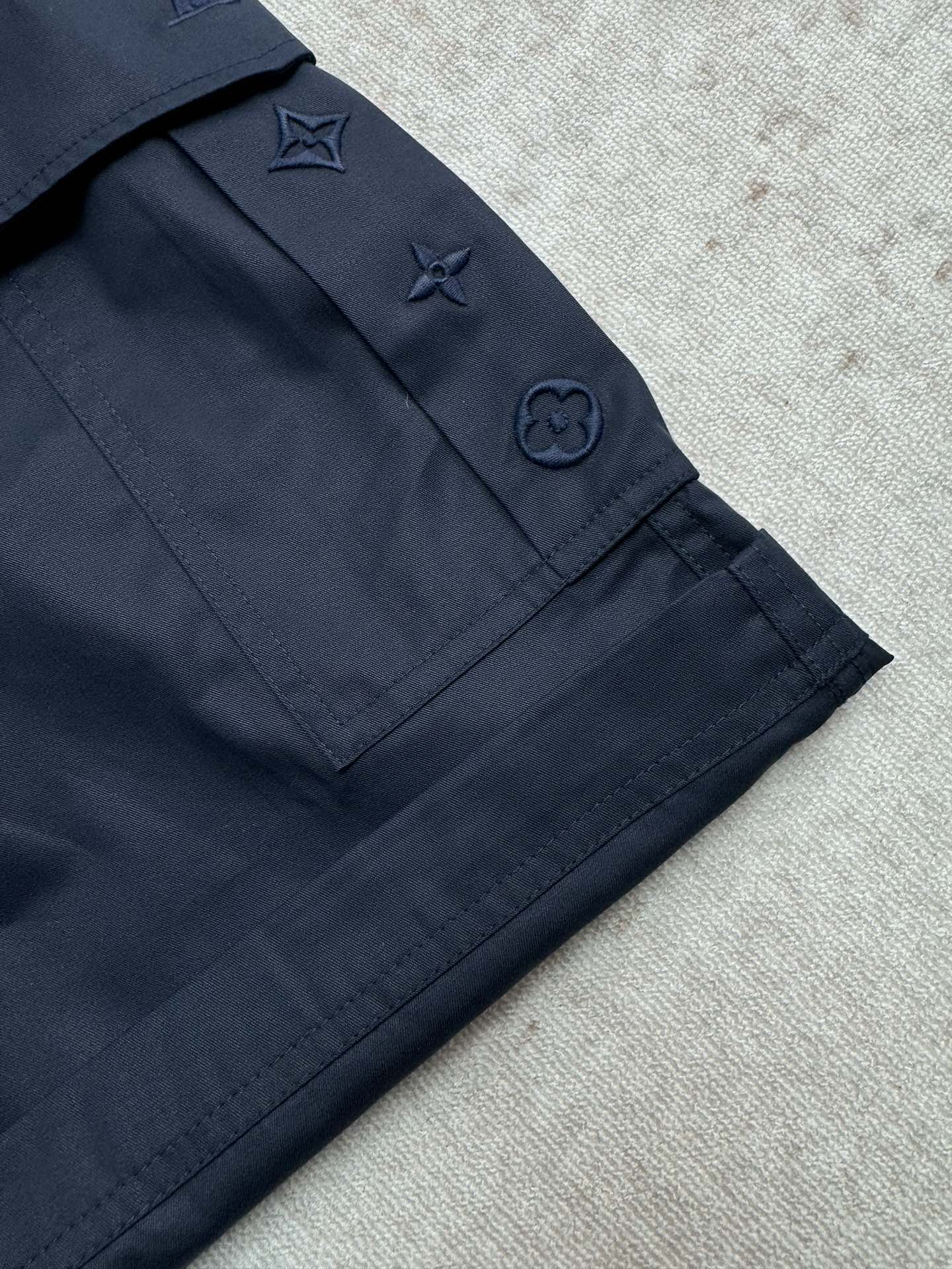Navy Louis Vuitton shorts with pocket flaps and embroidered star and icon details.
