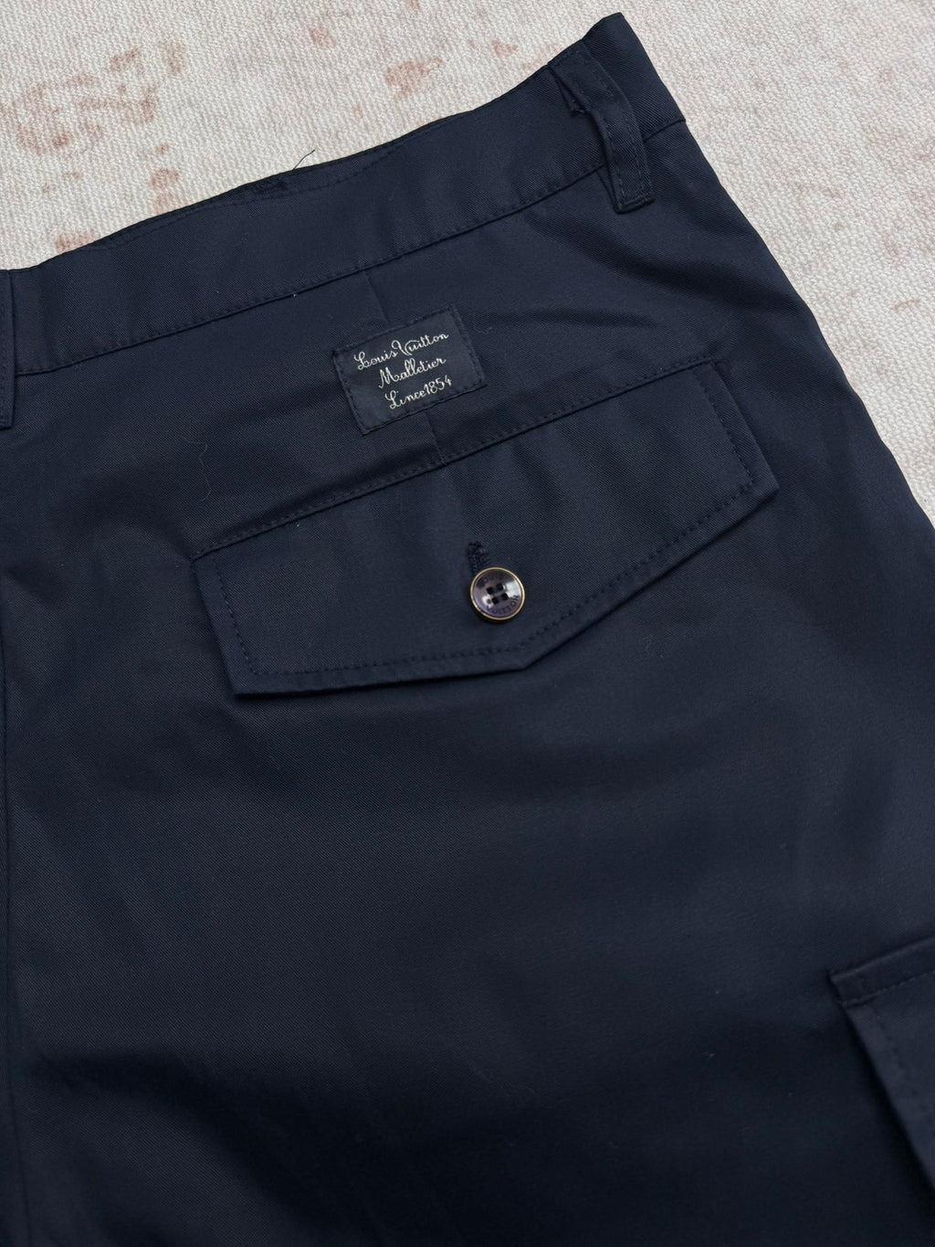 Navy Louis Vuitton shorts with front pocket and round button at waistband.