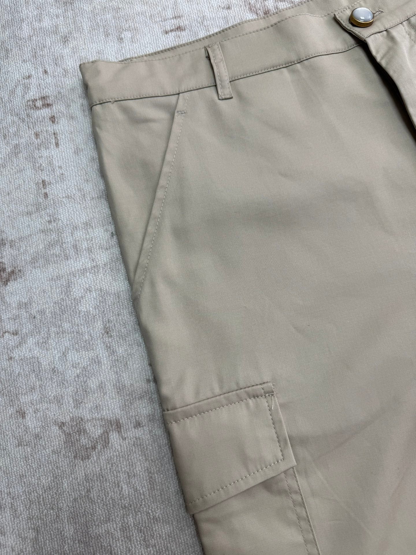 Beige shorts front close-up with pleated waistband and belt loops