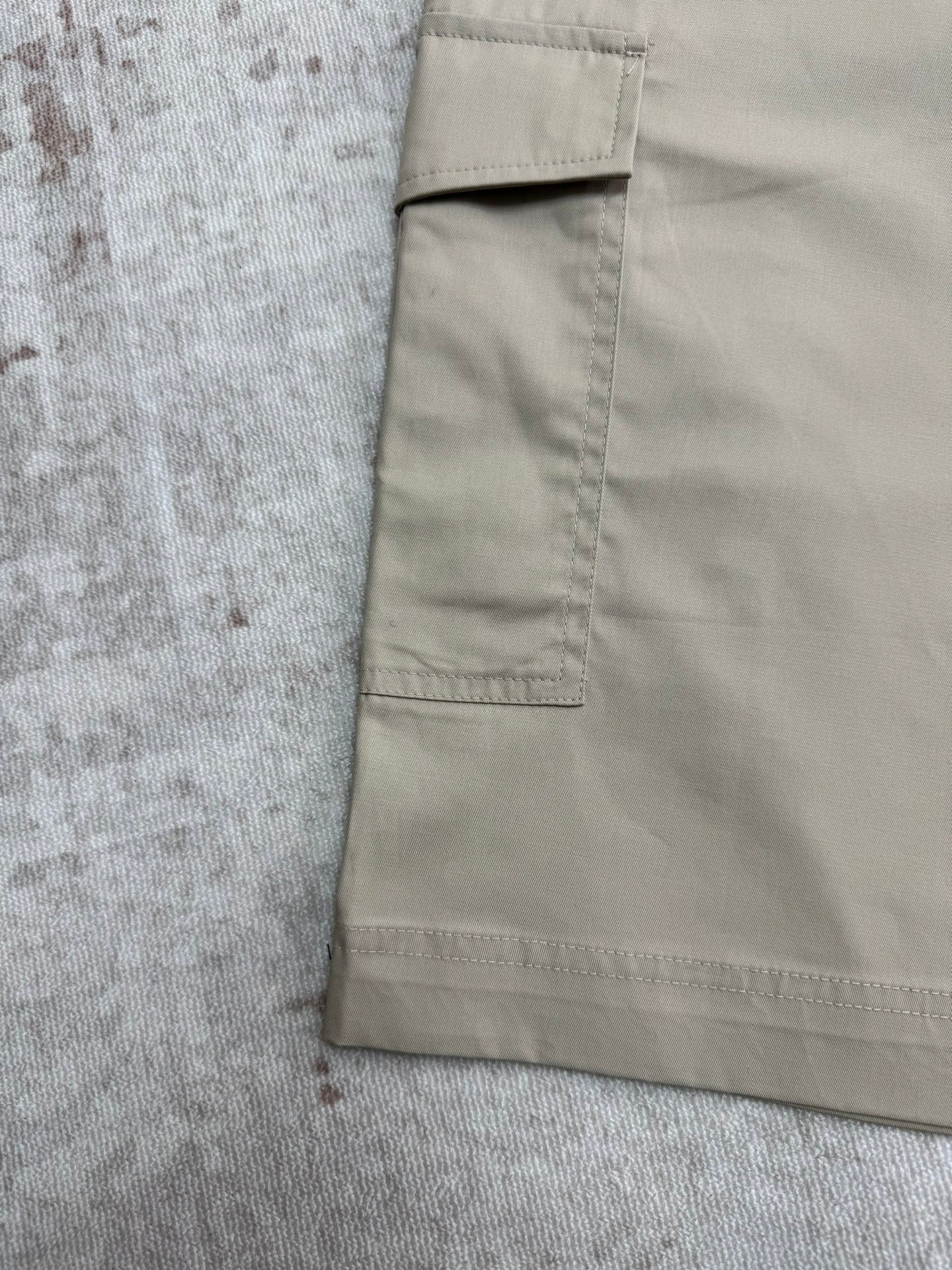 Beige cargo shorts side pocket and stitched seams close-up