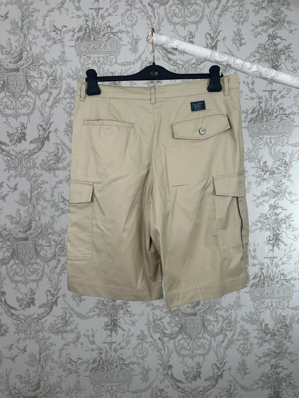Beige cargo shorts with side and back flap pockets, metal button