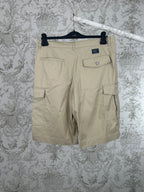 Beige cargo shorts with side and back flap pockets, metal button