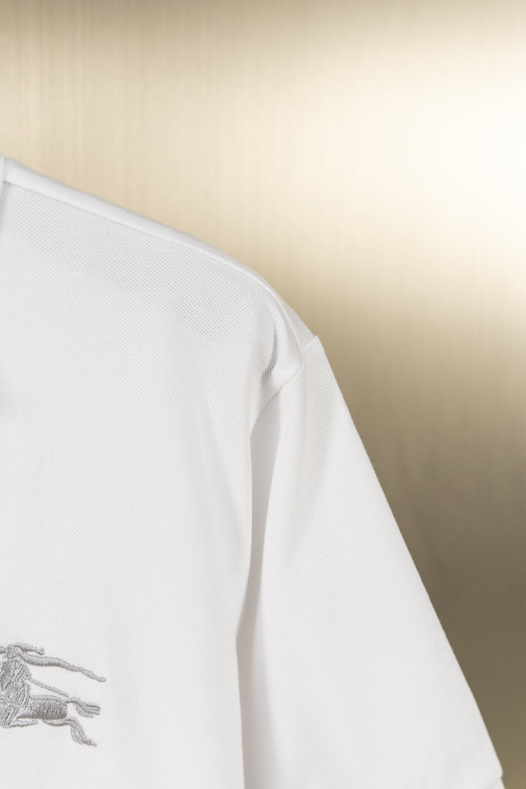 White polo shirt side view with short sleeve and embroidered logo detail