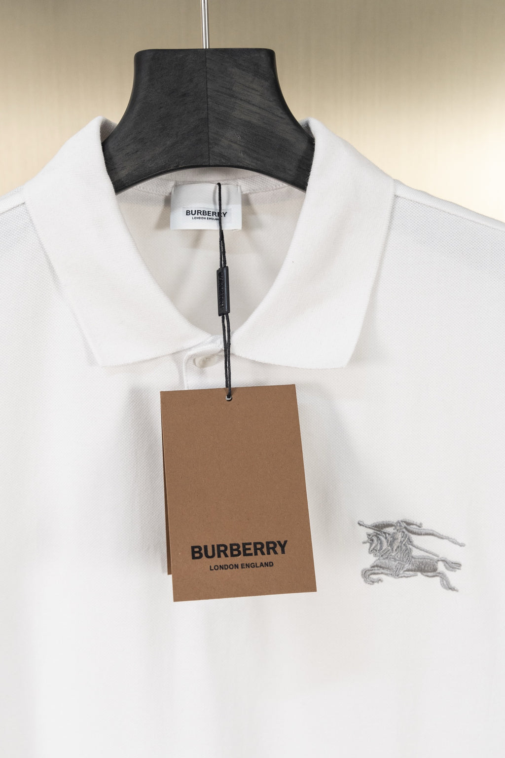 White polo shirt with short sleeves, placket collar, and hanging brand tag