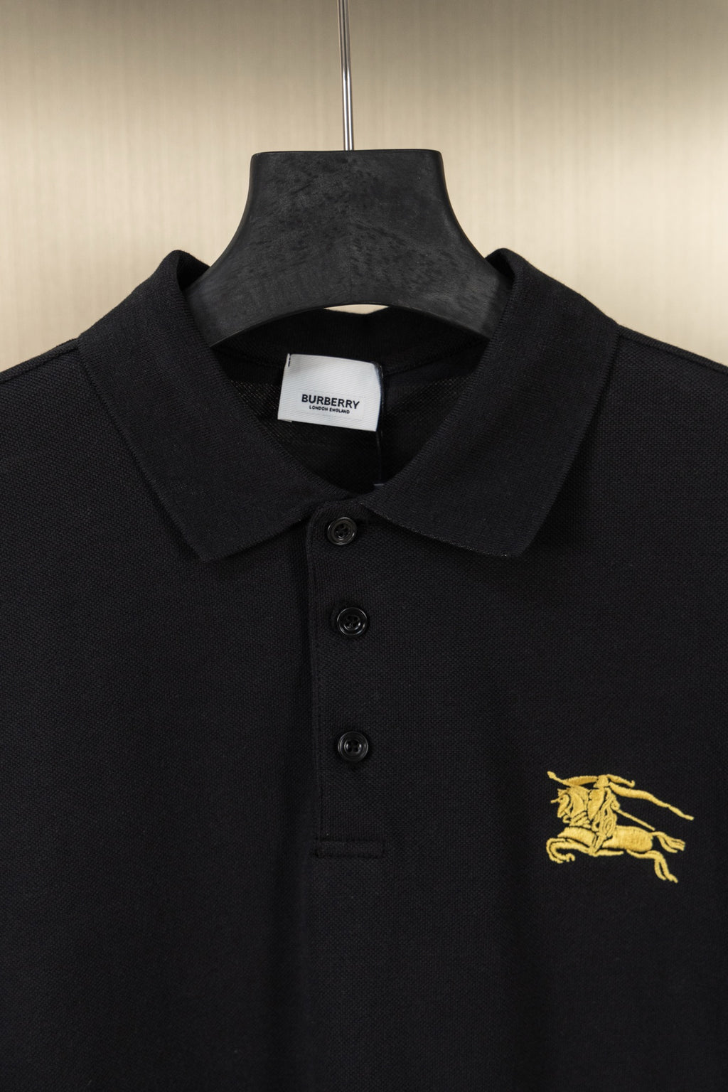 Burberry black polo shirt close-up of collar, buttons, and gold logo