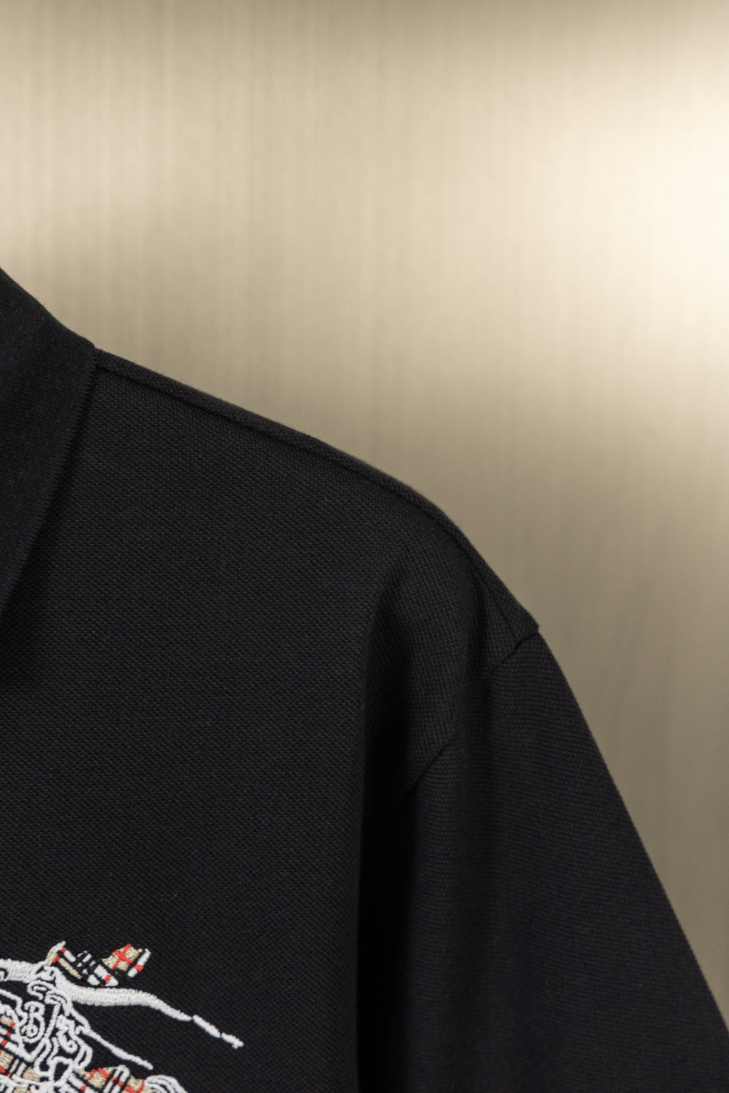 Black polo shirt shoulder seam with embroidered crest detail