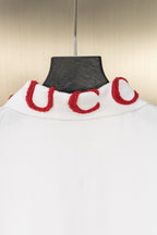 White polo shirt collar with red interlocking-letter embroidery