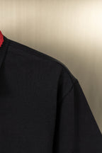 Black polo shirt sleeve and shoulder seam, textured knit fabric
