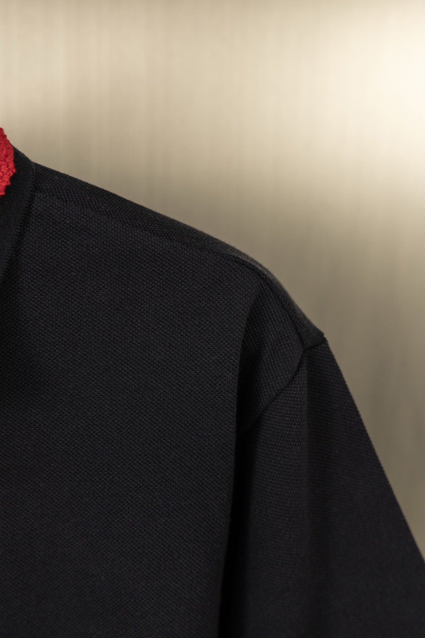 Black polo shirt sleeve and shoulder seam, textured knit fabric