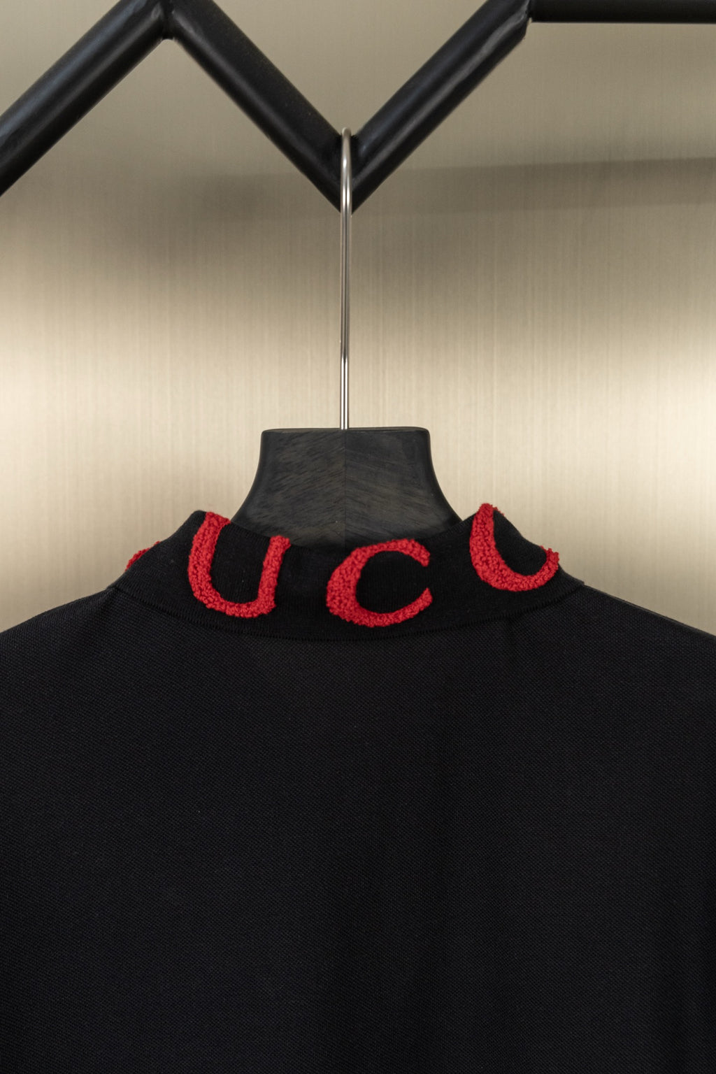 Black Gucci polo shirt collar, red embroidered logo letters at neckline