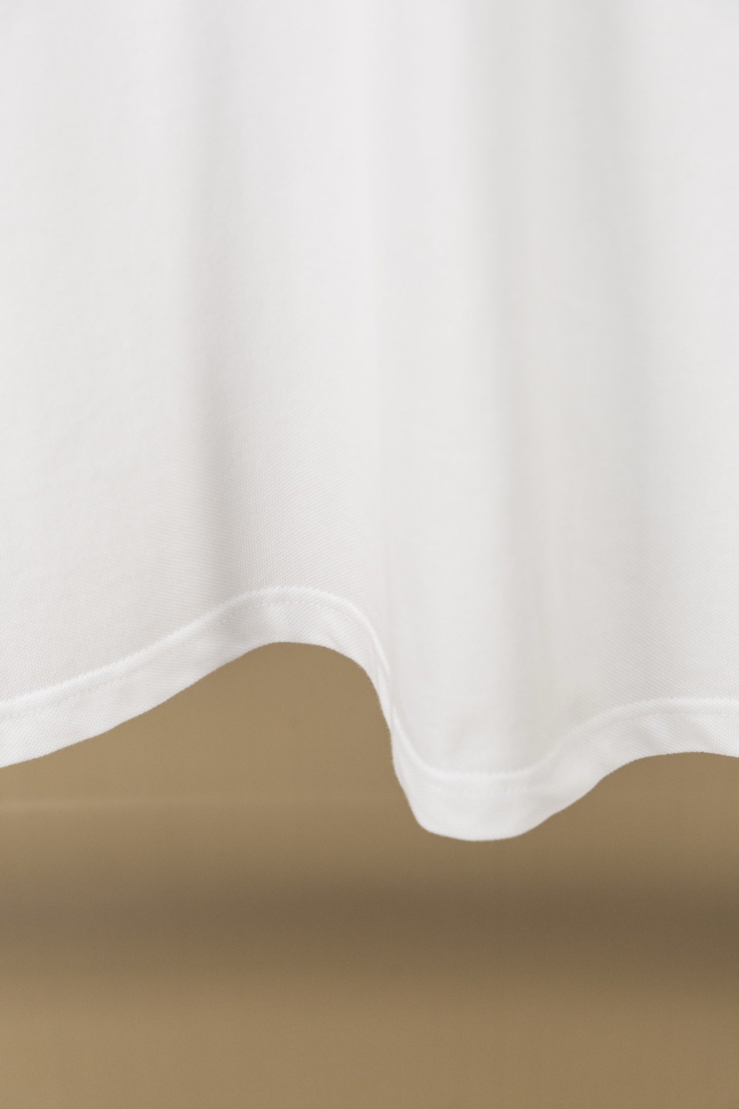 White polo shirt hem with curved bottom and visible stitching