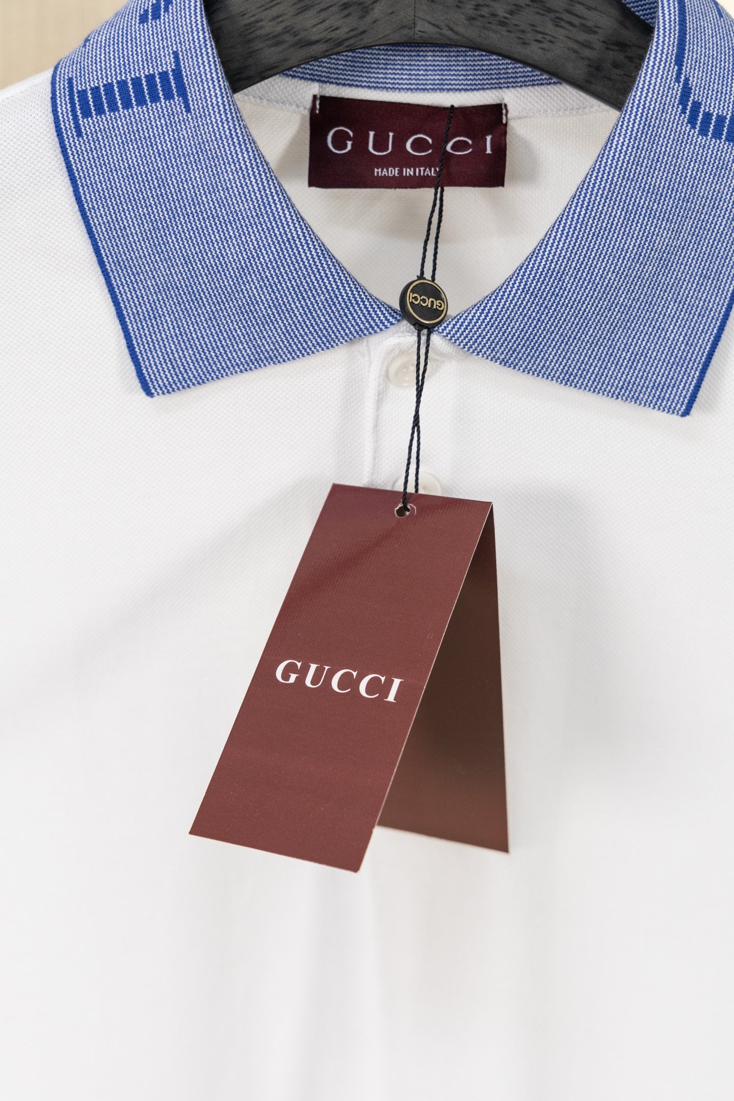 White polo shirt with blue logo collar and Gucci hang tag