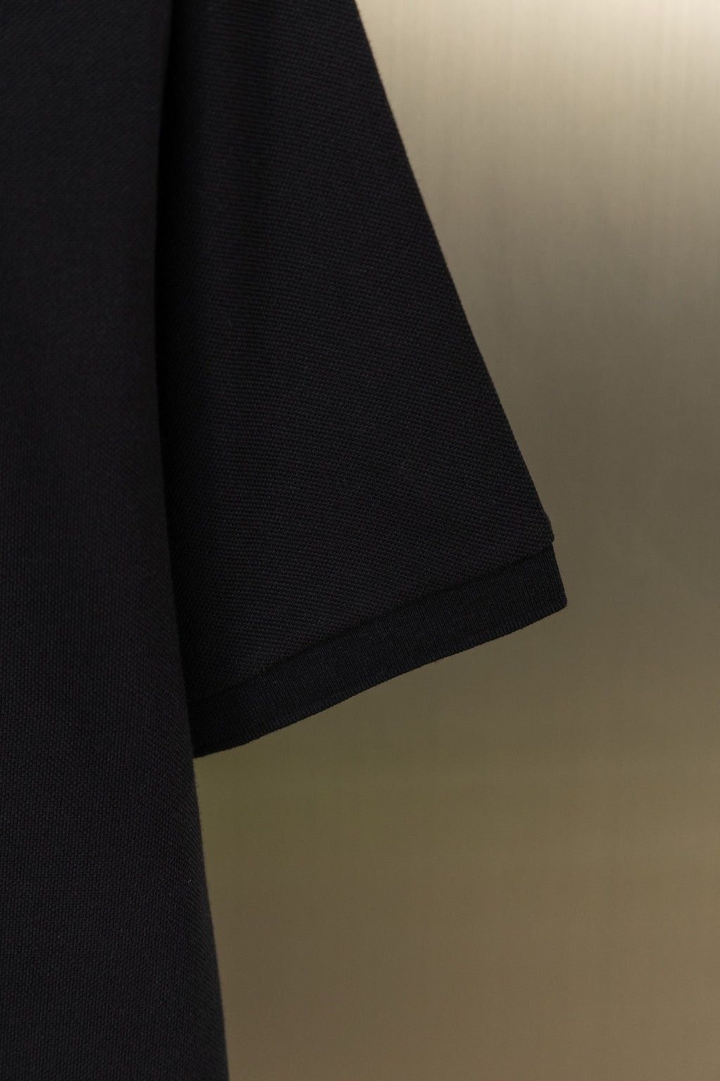 Black polo shirt lower sleeve hem detail