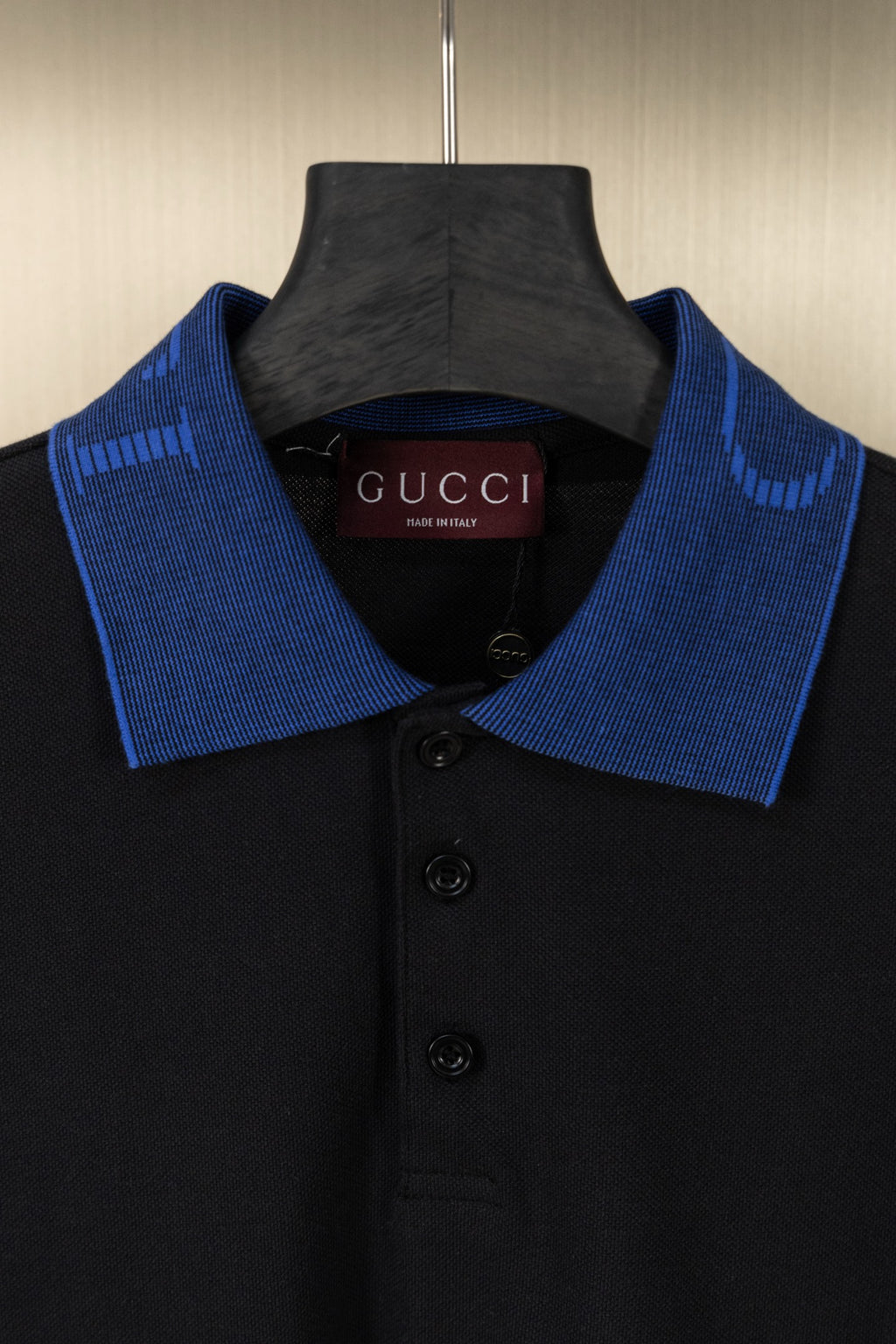 Black polo shirt neckline with blue knit collar and three black buttons
