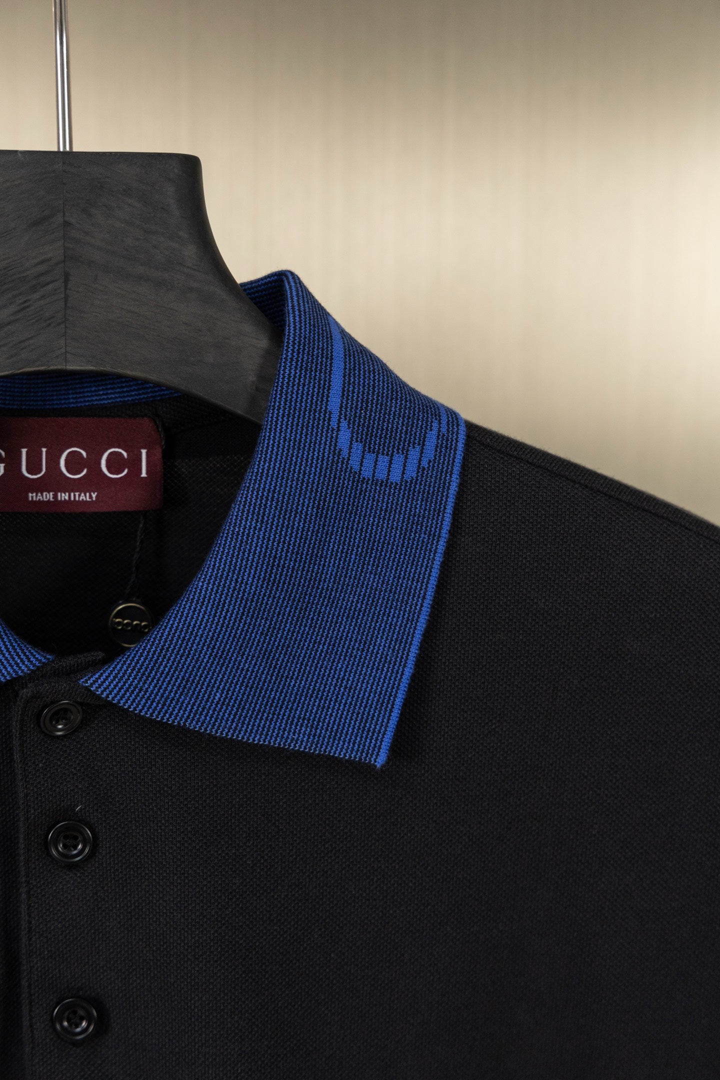 Black polo shirt shoulder with blue collar trim and buttons