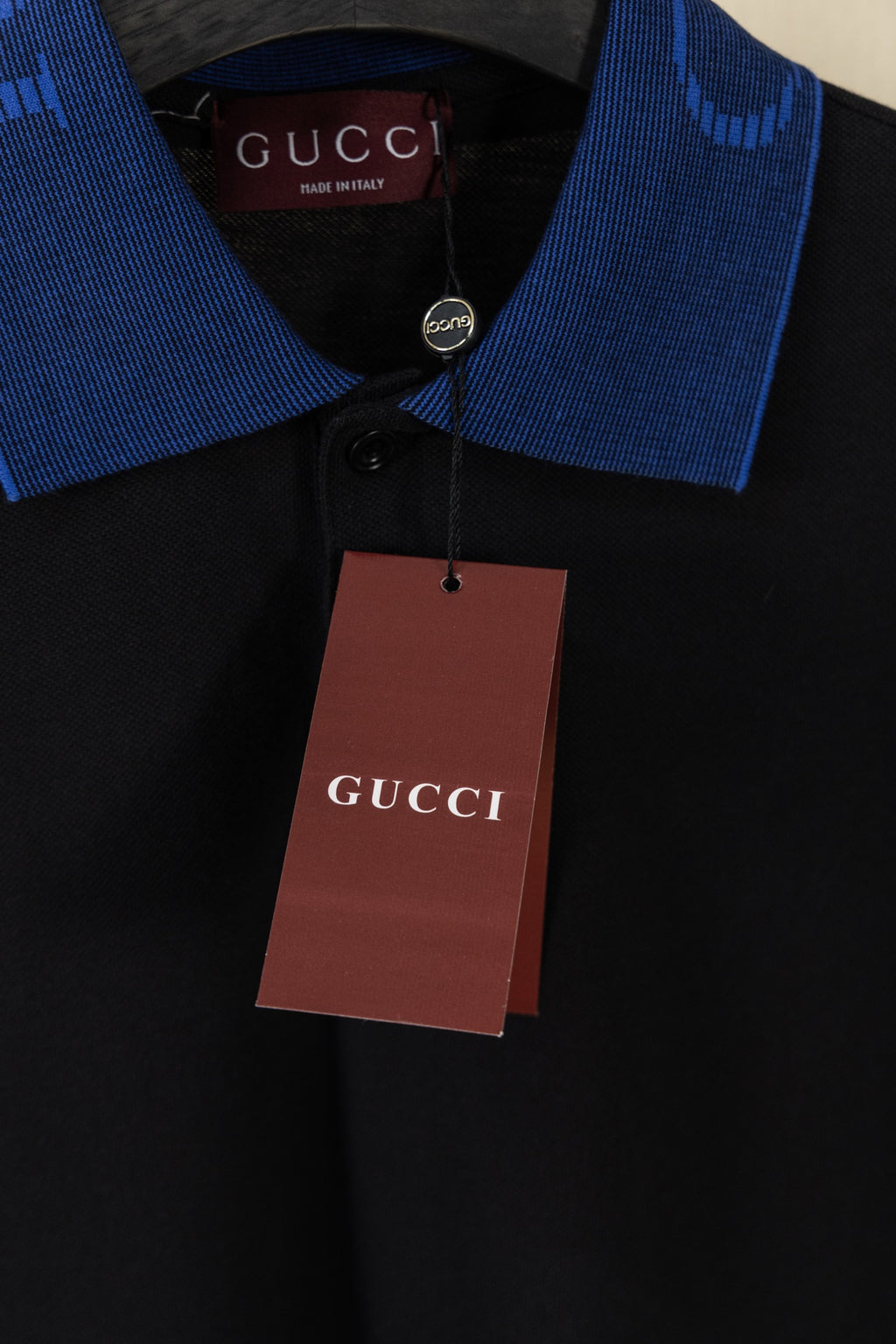 Black polo shirt with blue collar and hanging Gucci price tag